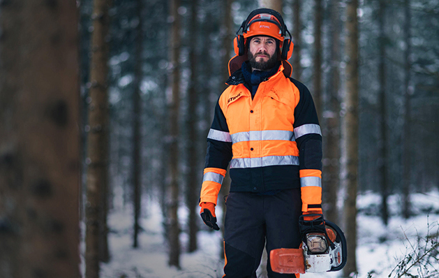 Il boscaiolo cammina con la motosega nella foresta invernale